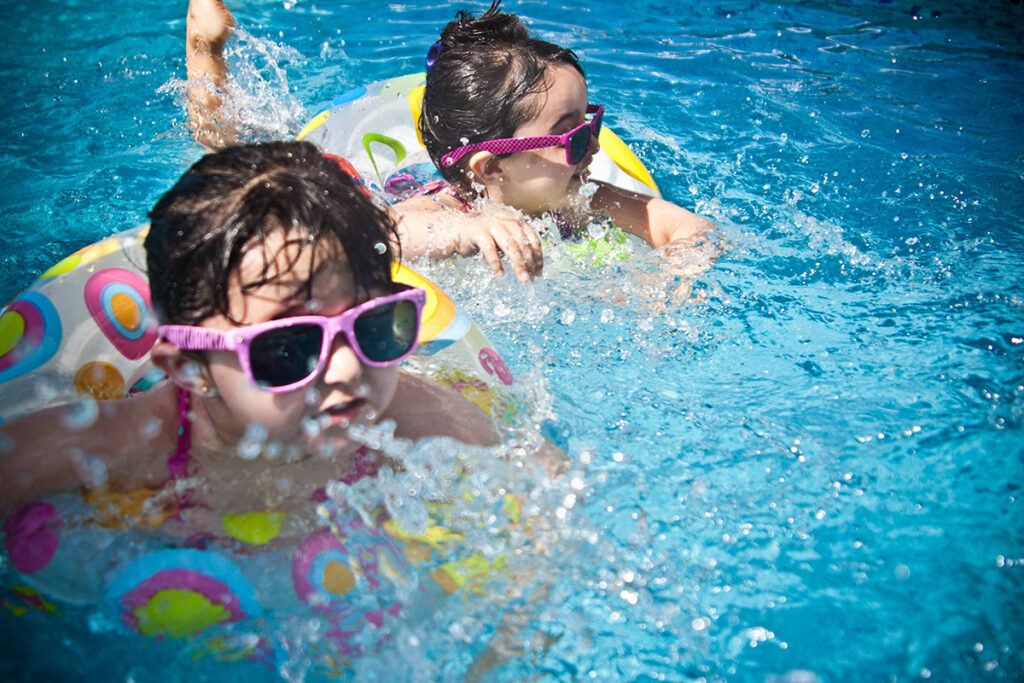 two kids in tubes swimming in backyard pool